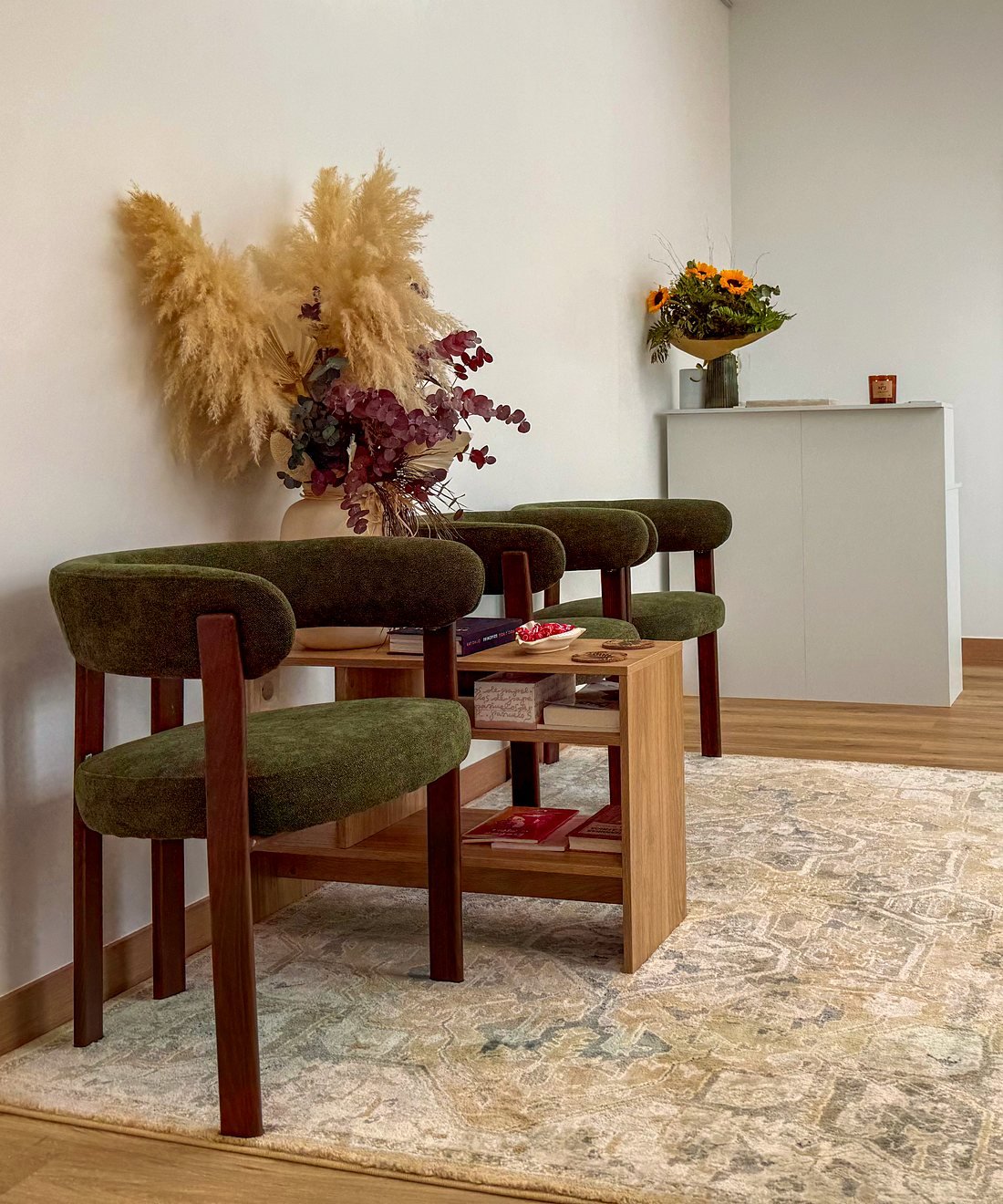 Sala de espera de Clínica Apolo en Puerto de Mazarrón, con butacas de terciopelo verde y flores secas